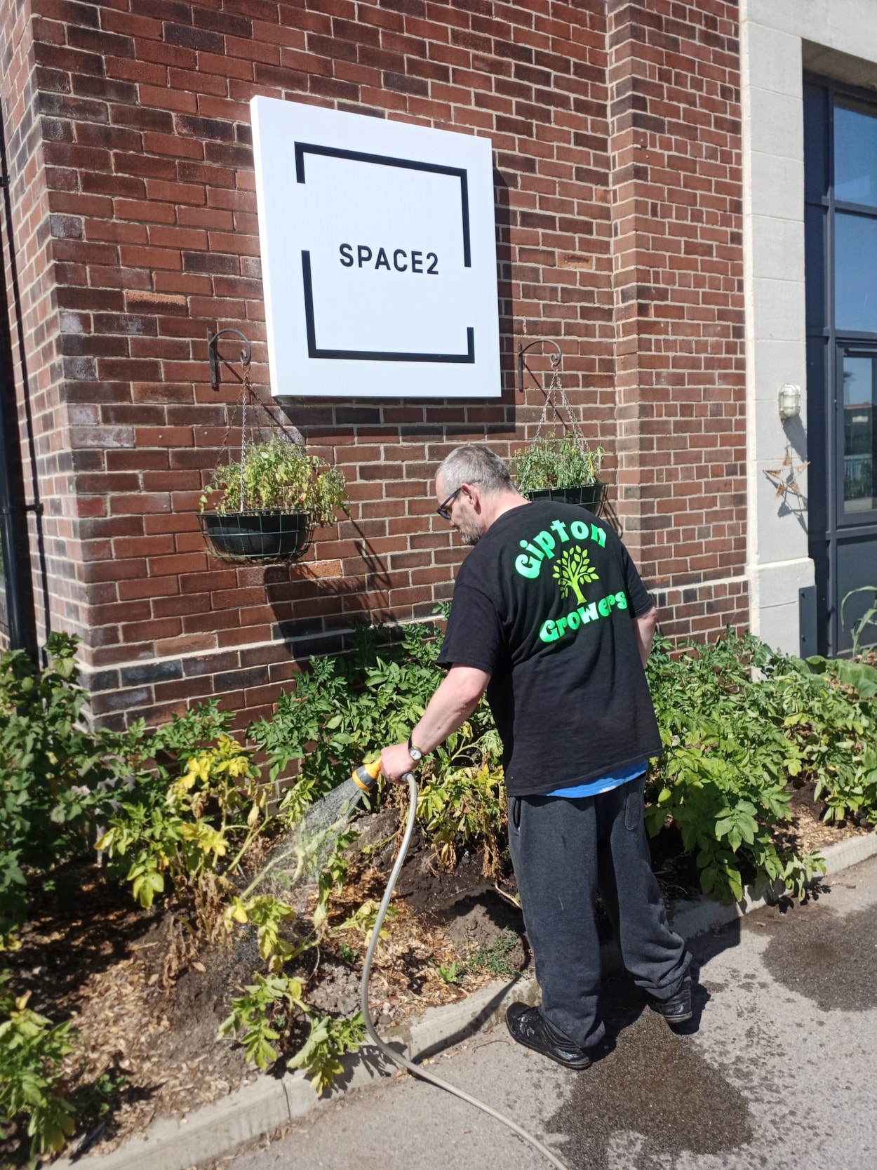 DPHAR 2026 - Gipton Growers: A member of the Space2's Gipton Growers watering the plants at their community garden at the Old Fire Station community hub.