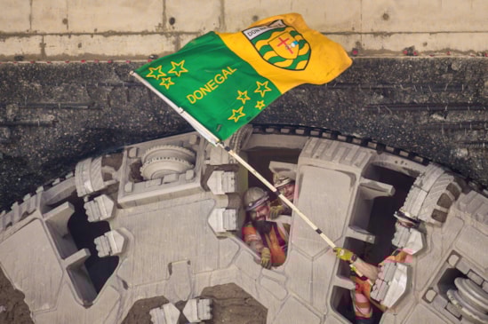 A tunneller waves the flag of Donegal through the cutterhead of TBM Elizabeth following the breakthrough Oct 2025